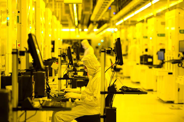 A picture of a semiconductor cleanroom with workers manufacturing microchips.